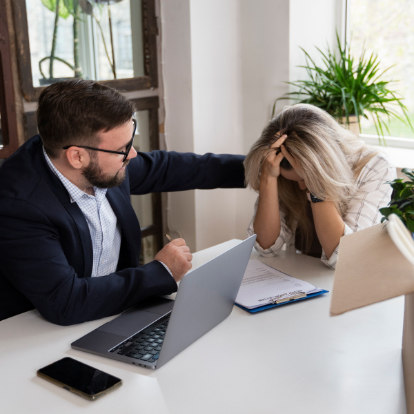 Un homme et une femme assis à un bureau, travaillant sur un ordinateur portable.