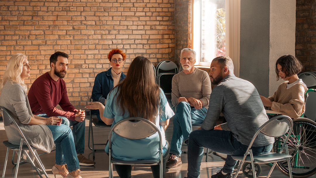 Un groupe de personnes discute autour d'une table, échangeant des idées sur l'innovation sociale.