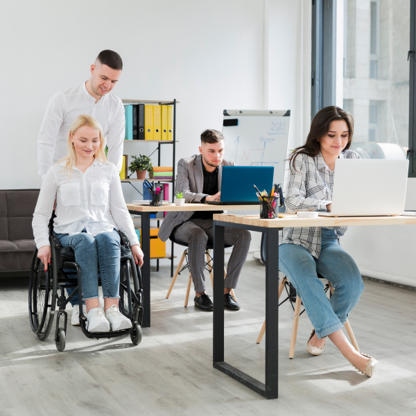 Un groupe de personnes dans un bureau, avec une femme en fauteuil roulant, discutant de la transition numérique.